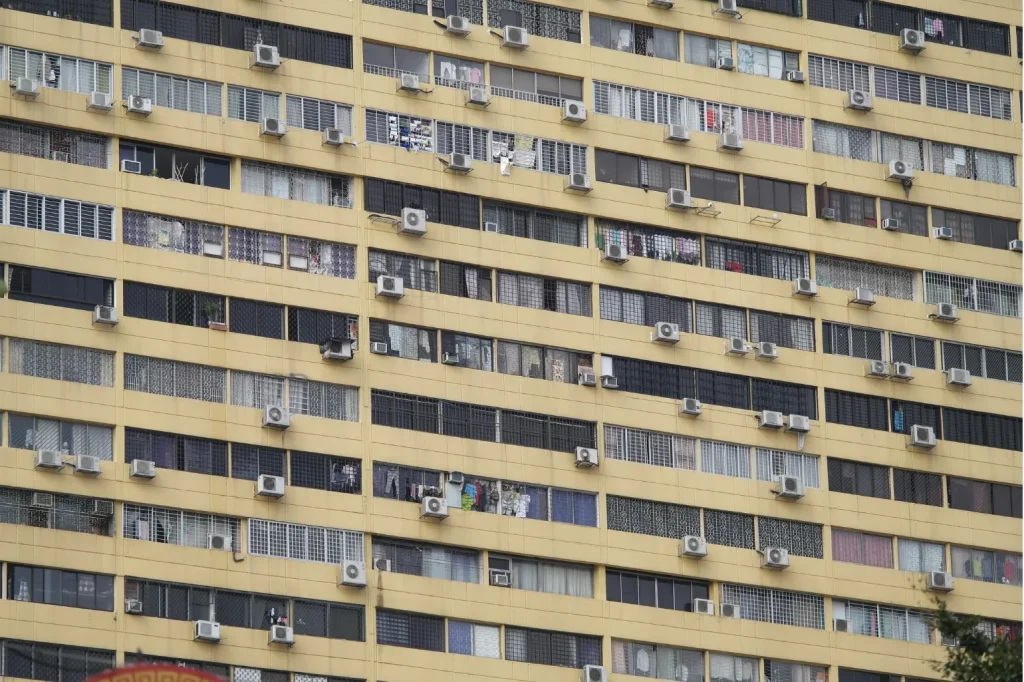 Singapore residential building with numerous air conditioning units, illustrating hybrid cooling solutions and energy savings.