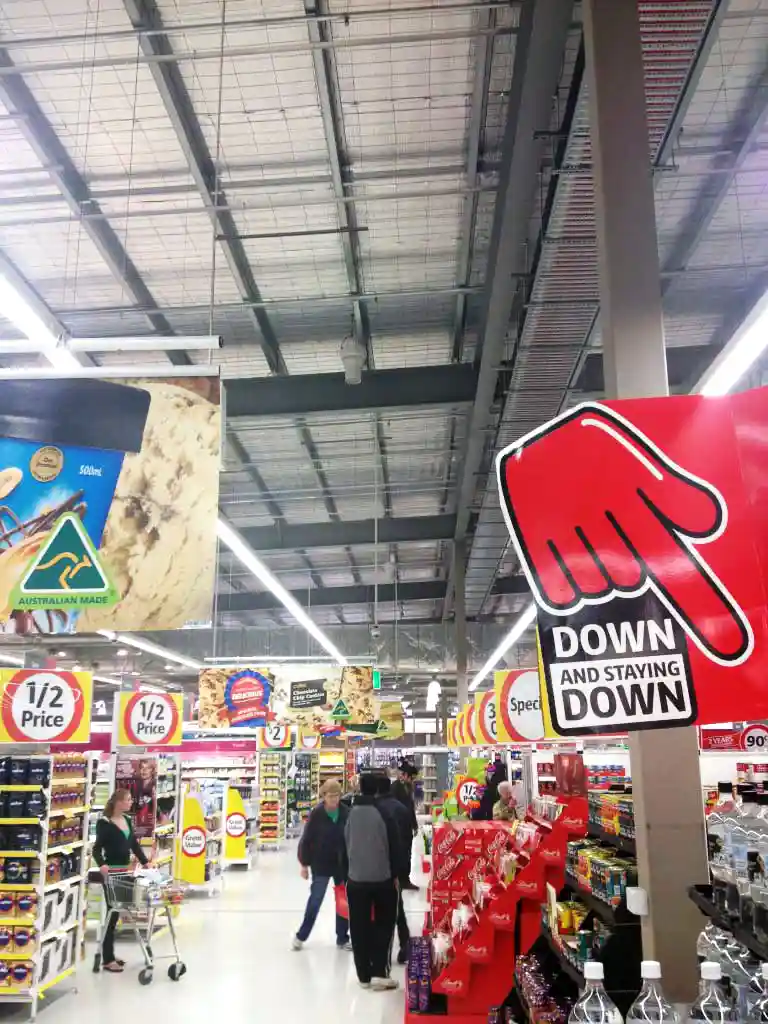 Supermarket interior with Airius cooling fans and promotional signage for improved air circulation and reduced