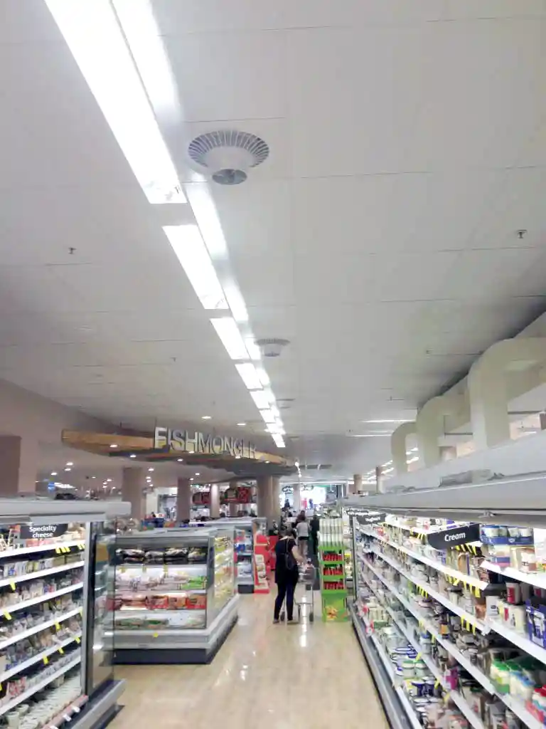 Supermarket aisle with Airius cooling fans improving air circulation and reducing condensation on freezer displays.