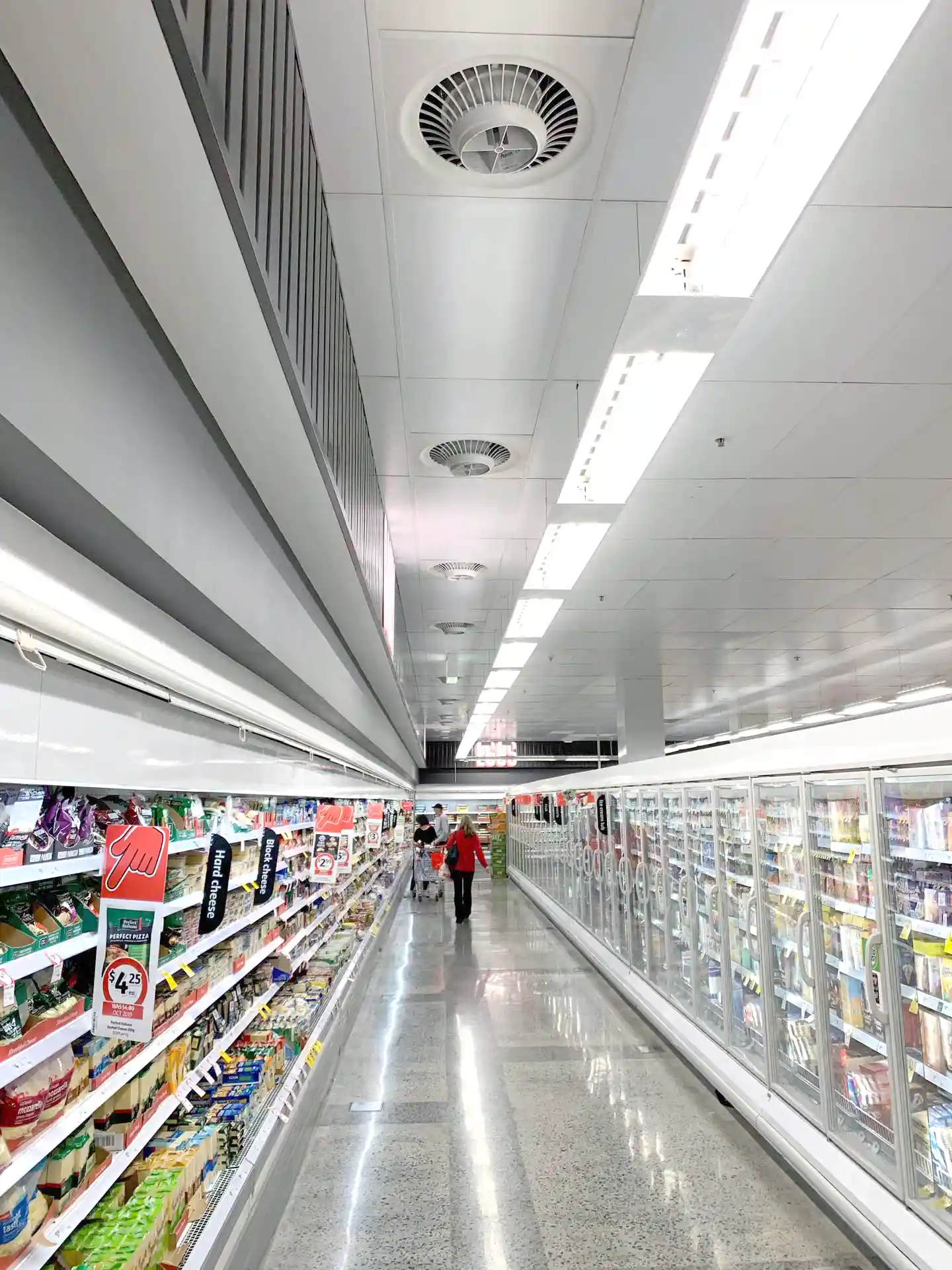 Supermarket aisle with Airius cooling fans and refrigeration units, improving air circulation and reducing condensation.