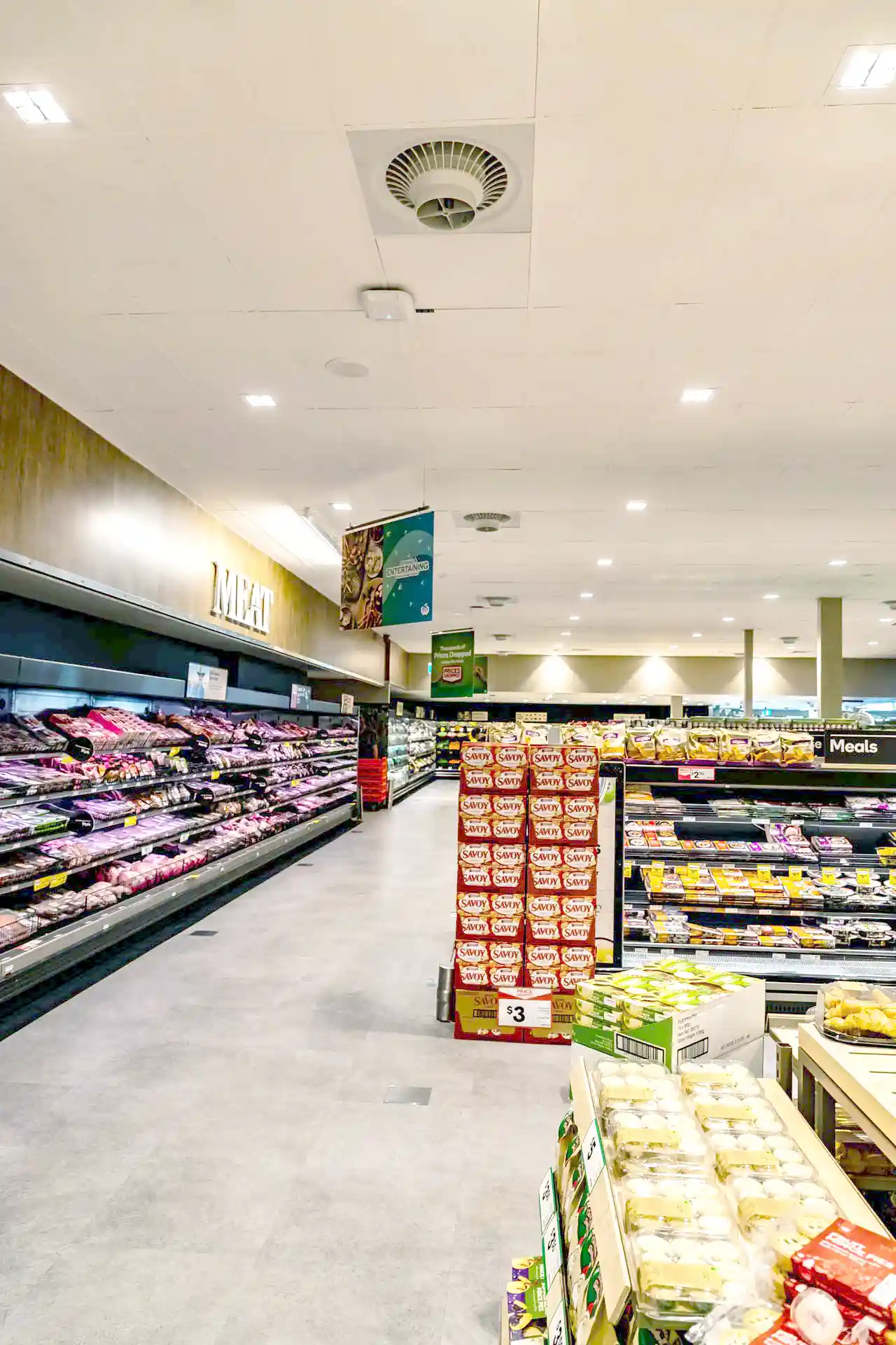 Supermarket interior with Airius cooling fans improving air circulation and reducing condensation on freezer displays.