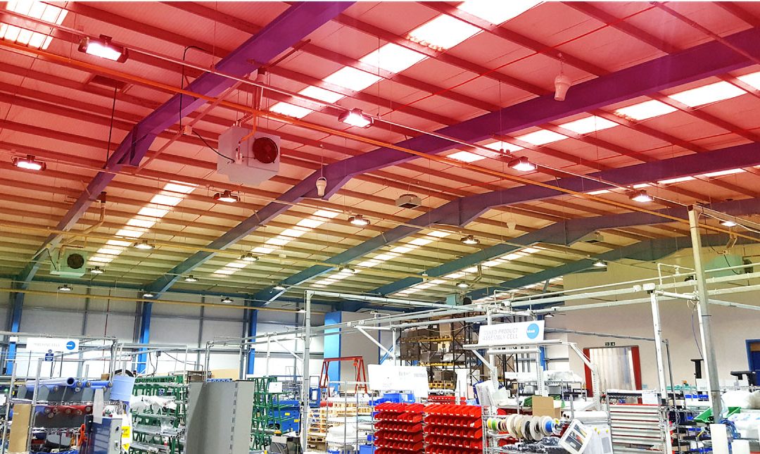 Large industrial warehouse ceiling with Airius destratification fans and lighting, improving air circulation and reducing